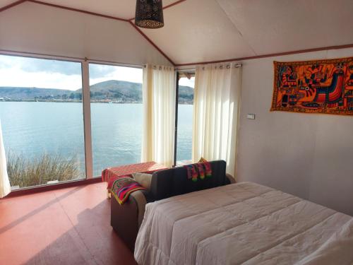 Coila Titicaca lodge في بونو: غرفة نوم بسرير وإطلالة على الماء