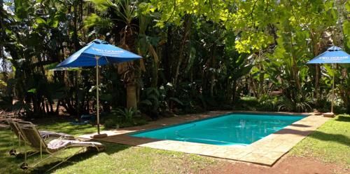 a swimming pool with an umbrella and a chair at Pumulani Lodge in Pretoria