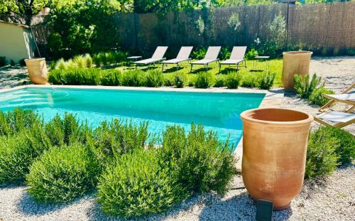 a swimming pool in a backyard with lounge chairs and plants at La Villa Bohème in Oppède