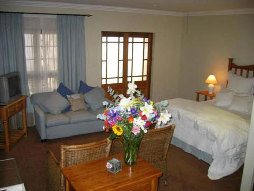 a bedroom with a bed and a vase of flowers on a table at Pumulani Lodge in Pretoria