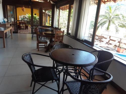 a table and chairs in a restaurant with a pool at Pousada Éden in Angra dos Reis