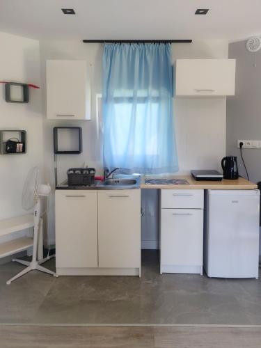 a kitchen with white cabinets and a sink and a blue curtain at Chatka in Stegienka
