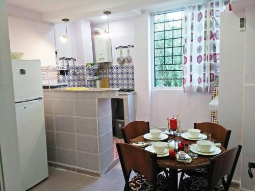 eine Küche mit einem Tisch und Stühlen sowie eine Küche mit einem Kühlschrank in der Unterkunft Appartement cosy tout équipé centre-ville, Tlemcen in Tlemcen