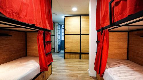 Habitación con 3 literas y cortinas rojas. en Fit Hostel Madrid, en Madrid