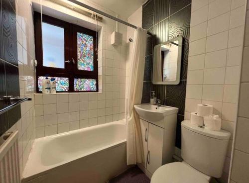 a bathroom with a toilet and a tub and a window at Fleetway Private Rooms in Central London in London