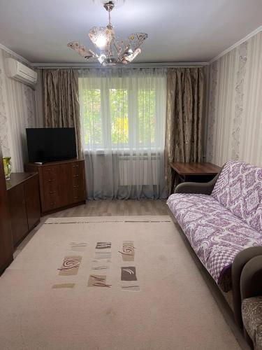 un soggiorno con divano e TV di Апартаменты на Ахметова 10 a Turksib