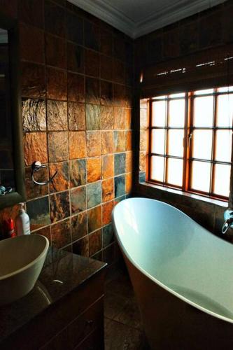 a bathroom with a bath tub and a sink at The Yellow House in Brits
