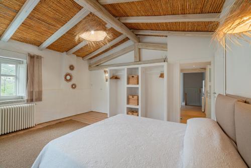 a bedroom with a white bed and a wooden ceiling at Villa Aromata in Trudda