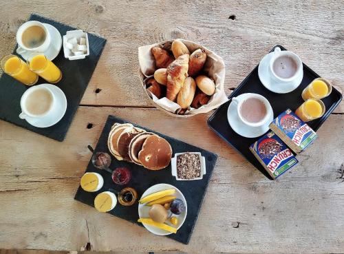 a table with plates of breakfast foods and cups of coffee at LE COCON l'unique expérience Cinéma room de la Grange Savoyarde 1km du Lac d'Annecy in Lathuile