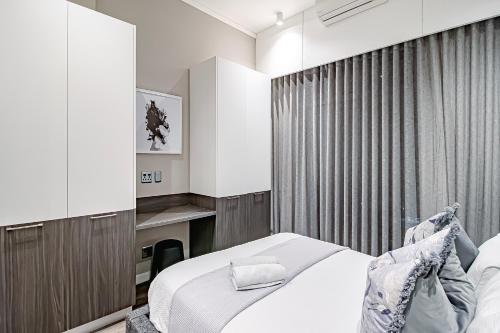 1 dormitorio con cama blanca y cortina en 2bedroom apartments at Menlyn Maine on 16th, en Pretoria