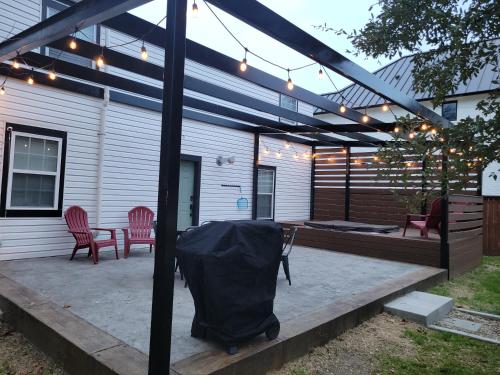a covered patio with a table and chairs and lights at Simply Get-A-Waco- HOT TUB, Sleeps 10, 5-min Walk to Silos & Downtown Waco in Waco