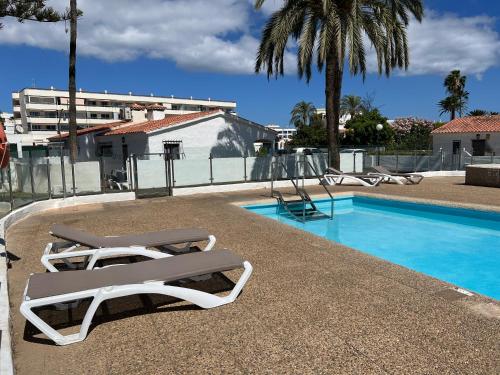 - une piscine avec 2 chaises longues et une balançoire dans l'établissement Relaxing Bungalow Playa del Inglés, à Maspalomas