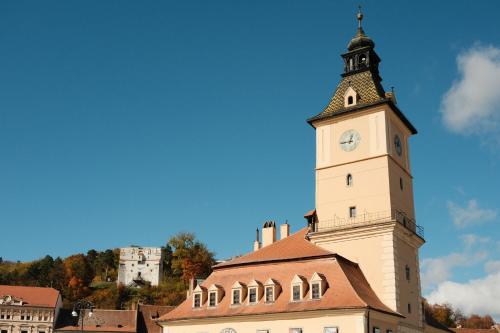 a building with a clock tower on top of it at MooDee Suite - Piata Sfatului in Braşov