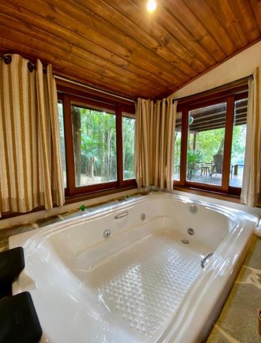 a large white tub in a room with windows at Pousada Varandas da Mantiqueira in São Francisco Xavier