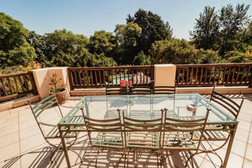 a glass table and chairs on a balcony at Blue Hills Lodge in Midrand