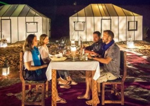 a group of people sitting at a dinner table at Luxury Desert Camp Merzouga in Merzouga