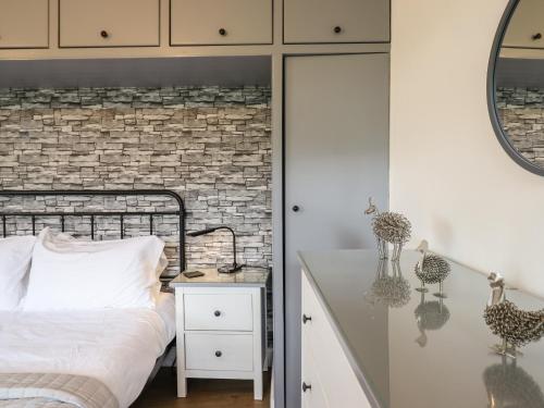 a bedroom with a bed and a brick wall at Pengeulan in Machynlleth