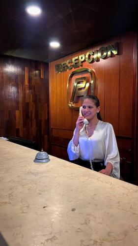 Una mujer sentada en una mesa hablando por celular en Park Hotel Mérida en Mérida