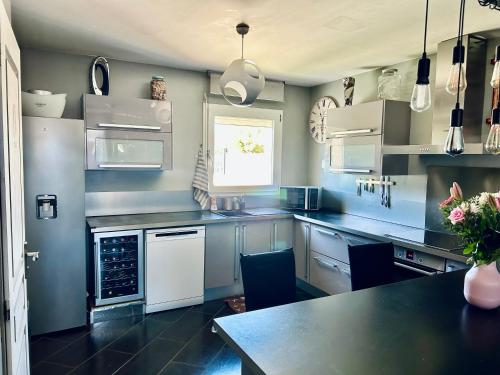 une cuisine avec des appareils blancs et un comptoir noir dans l'établissement villa avec jardin et piscine, à Vic-la-Gardiole