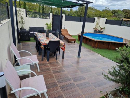 un patio avec une table et des chaises et une piscine dans l'établissement villa avec jardin et piscine, à Vic-la-Gardiole