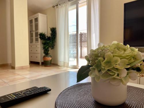 a vase of flowers on a table with a remote control at Penthouse with amazing terrace and Altea sea views in Altea