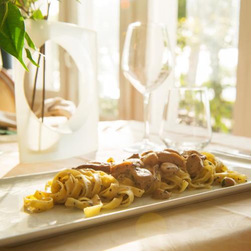 a plate of pasta on a table with wine glasses at Hotel Sinuessa Terme in Mondragone