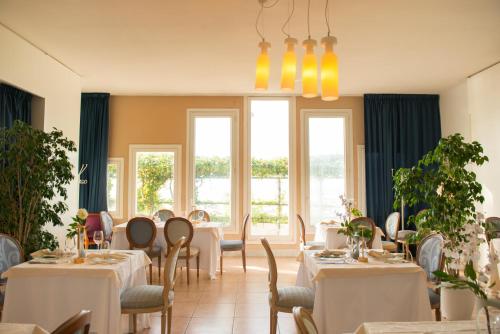 a dining room with tables and chairs and windows at Hotel Sinuessa Terme in Mondragone