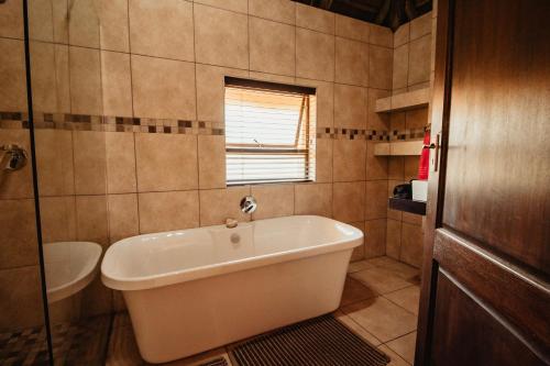 a bathroom with a bath tub and a sink at Blue Hills Lodge in Midrand