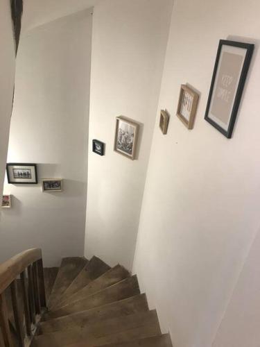 a hallway with a staircase with pictures on the wall at Appartement au coeur du vignoble tonnerrois in Tonnerre