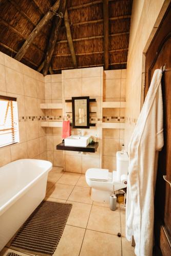 a bathroom with a tub and a toilet and a sink at Blue Hills Lodge in Midrand