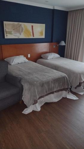 a hotel room with two beds and a couch at Conforto no Coração da Barra in Rio de Janeiro