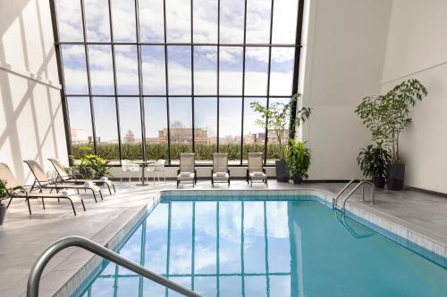 a pool in a hotel with chairs and a large window at Renaissance Denver Central Park Hotel in Denver