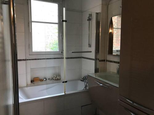 une salle de bain avec une baignoire, un lavabo et une fenêtre dans l'établissement Appart 2 pièce 52 m2 vue jardin, à Paris