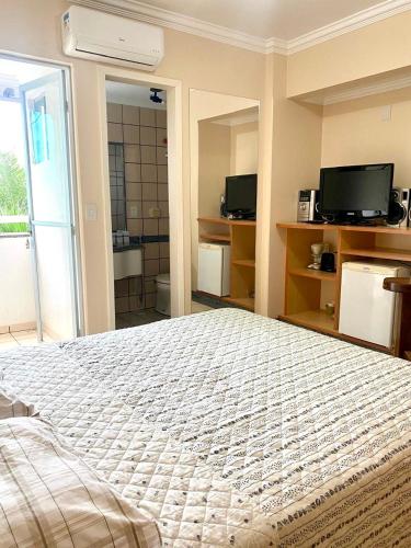 a bedroom with a large bed and a television at Flat perto dos parques termais in Rio Quente