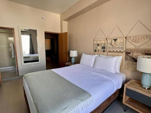1 dormitorio con 1 cama grande con almohadas blancas en La Mona Suites - Cozy 1 BR with Full Kitchen, en San Juan