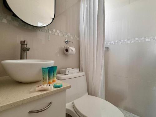 y baño con aseo, lavabo y espejo. en La Mona Suites - Cozy 1 BR with Full Kitchen, en San Juan