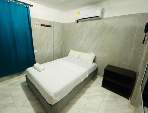 Un pequeño dormitorio con una cama blanca y una cortina azul en Hotel Rancho Grande, en Barranquilla