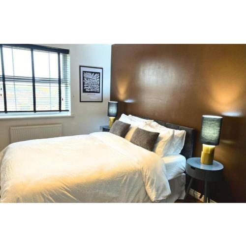 a bedroom with a large bed with white sheets and pillows at Stunning stay 6 minutes from NEC and Birmingham Airport in Solihull