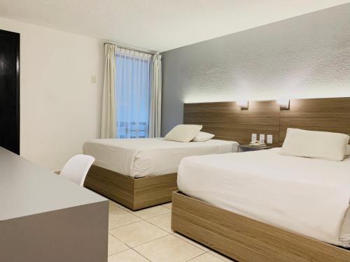 a hotel room with two beds and a window at Hotel Beddo Express Querétaro in Querétaro