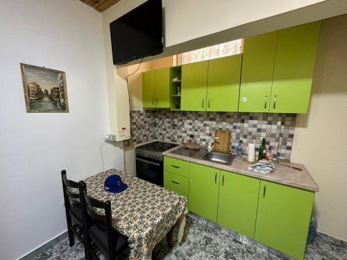 a small kitchen with green cabinets and a table at Chicago hotel in Fier
