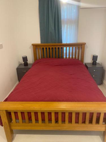 sypialnia z drewnianym łóżkiem z czerwoną narzutą w obiekcie A whole fully equipped 1 bedroom property w mieście Woodford