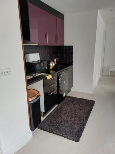 małą kuchnię z kuchenką i fioletowymi szafkami w obiekcie A whole fully equipped 1 bedroom property w mieście Woodford