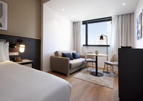 マラガにあるHotel Málaga Alameda Centro Affiliated by Meliáのベッドルーム1室(ベッド1台付)、リビングルームが備わります。