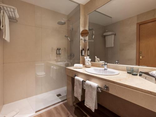 een badkamer met een wastafel, een douche en een spiegel bij Hotel Málaga Alameda Centro Affiliated by Meliá in Málaga