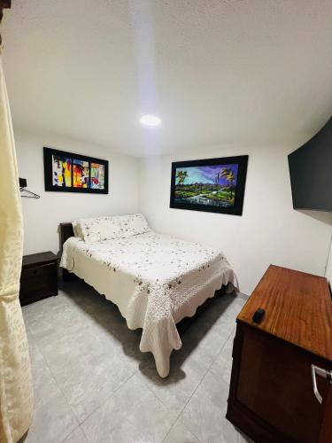 Un dormitorio con una cama y un televisor en la pared. en Apartamento Aamayu, en Villa de Leyva