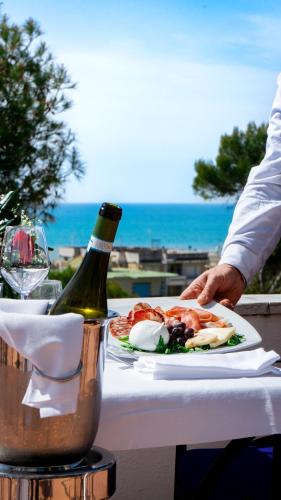 a table with a plate of food and a bottle of wine at Hotel Sinuessa Terme in Mondragone