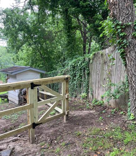 a wooden fence with a gate next to a house at Pet friendly Tiny House Rental with new Access to Guadalupe River NBTX in New Braunfels