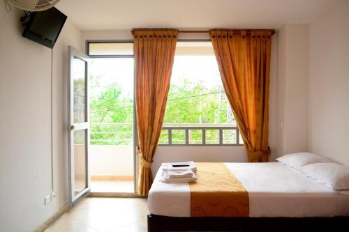 a bedroom with a bed and a large window at Hotel Tropico Real Mesitas in El Colegio