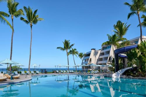 a pool at the resort with palm trees and a slide at OUTRIGGER Kona Resort and Spa in Kailua-Kona