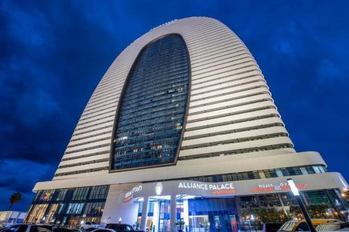 a large building with a curved tower with cars parked in front at Premium apartments - the star of Batumi Palace in Batumi